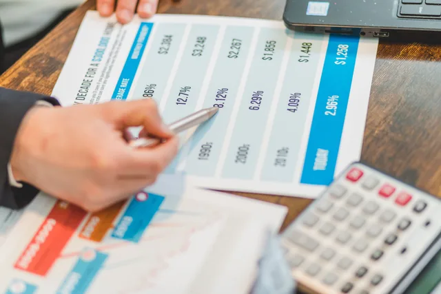 Close-up of financial documents with charts and a calculator used for business analysis. Judging business checking services on evidence, not brochures