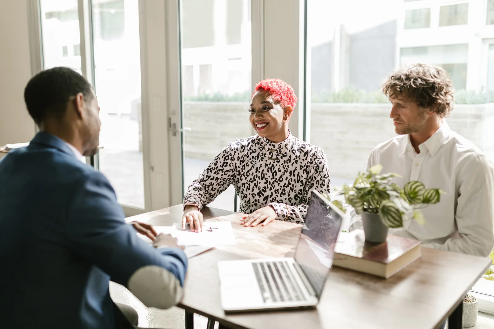 Three professionals meeting in a sunny office discussing finance with smiles. Credit unions: which services to weigh for your business